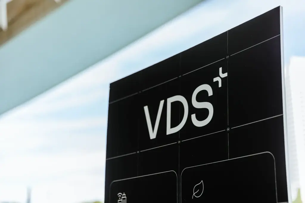 Close-up of a black vertical sign with large white letters 'VDS' and grid marks, outdoors.