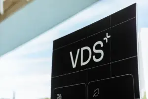 Close-up of a black vertical sign with large white letters 'VDS' and grid marks, outdoors.